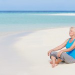 woman over 50 meditating on a beach